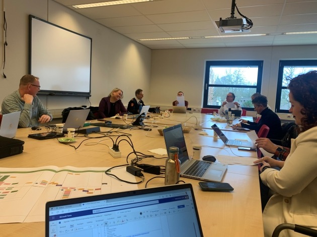 Meerdere mensen aan een tafel met laptops 